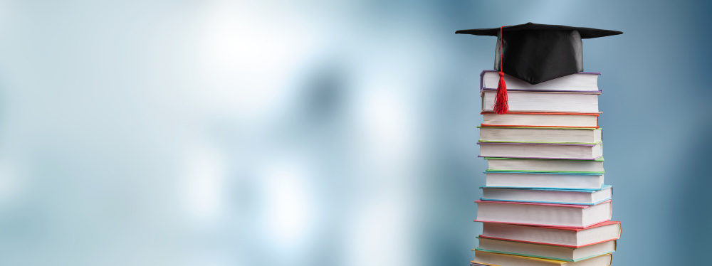 Pile of books with graduation cap on top